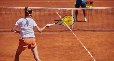Profesyonel bir tenisçi ve onun koçu tenis kortunda güneşli bir günde antrenman yapıyorlar. Profesyonel bir tenisçinin antrenmanı ve hazırlığı.