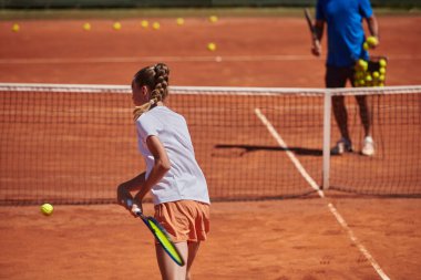 Profesyonel bir tenisçi ve onun koçu tenis kortunda güneşli bir günde antrenman yapıyorlar. Profesyonel bir tenisçinin antrenmanı ve hazırlığı.