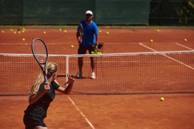 Profesyonel bir tenisçi ve onun koçu tenis kortunda güneşli bir günde antrenman yapıyorlar. Profesyonel bir tenisçinin antrenmanı ve hazırlığı.