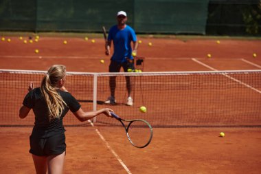 Profesyonel bir tenisçi ve onun koçu tenis kortunda güneşli bir günde antrenman yapıyorlar. Profesyonel bir tenisçinin antrenmanı ve hazırlığı.