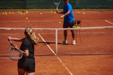 Profesyonel bir tenisçi ve onun koçu tenis kortunda güneşli bir günde antrenman yapıyorlar. Profesyonel bir tenisçinin antrenmanı ve hazırlığı.