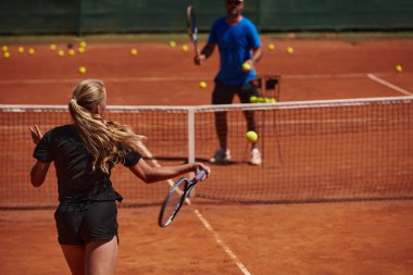 Profesyonel bir tenisçi ve onun koçu tenis kortunda güneşli bir günde antrenman yapıyorlar. Profesyonel bir tenisçinin antrenmanı ve hazırlığı.