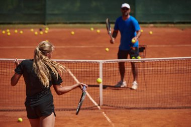 Profesyonel bir tenisçi ve onun koçu tenis kortunda güneşli bir günde antrenman yapıyorlar. Profesyonel bir tenisçinin antrenmanı ve hazırlığı.