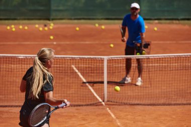 Profesyonel bir tenisçi ve onun koçu tenis kortunda güneşli bir günde antrenman yapıyorlar. Profesyonel bir tenisçinin antrenmanı ve hazırlığı.