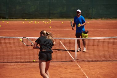 Profesyonel bir tenisçi ve onun koçu tenis kortunda güneşli bir günde antrenman yapıyorlar. Profesyonel bir tenisçinin antrenmanı ve hazırlığı.