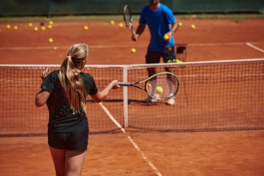 Profesyonel bir tenisçi ve onun koçu tenis kortunda güneşli bir günde antrenman yapıyorlar. Profesyonel bir tenisçinin antrenmanı ve hazırlığı.
