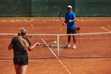 Profesyonel bir tenisçi ve onun koçu tenis kortunda güneşli bir günde antrenman yapıyorlar. Profesyonel bir tenisçinin antrenmanı ve hazırlığı.