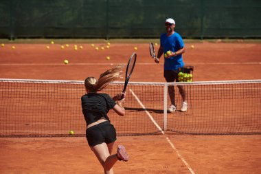 Profesyonel bir tenisçi ve onun koçu tenis kortunda güneşli bir günde antrenman yapıyorlar. Profesyonel bir tenisçinin antrenmanı ve hazırlığı.