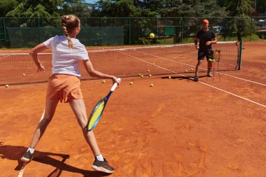 Profesyonel bir tenisçi ve onun koçu tenis kortunda güneşli bir günde antrenman yapıyorlar. Profesyonel bir tenisçinin antrenmanı ve hazırlığı.