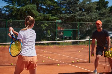 Profesyonel bir tenisçi ve onun koçu tenis kortunda güneşli bir günde antrenman yapıyorlar. Profesyonel bir tenisçinin antrenmanı ve hazırlığı.
