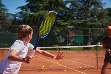 Profesyonel bir tenisçi ve onun koçu tenis kortunda güneşli bir günde antrenman yapıyorlar. Profesyonel bir tenisçinin antrenmanı ve hazırlığı.