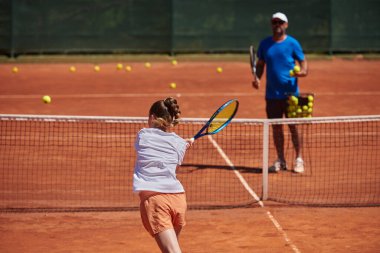 Profesyonel bir tenisçi ve onun koçu tenis kortunda güneşli bir günde antrenman yapıyorlar. Profesyonel bir tenisçinin antrenmanı ve hazırlığı.