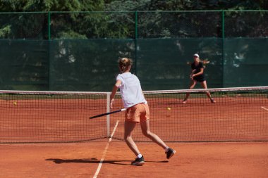 Genç kızlar güneşli bir günde canlı bir tenis maçında modern bir tenis kortunda yeteneklerini ve heveslerini gösteriyorlar.