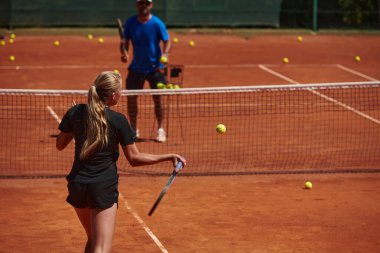 Profesyonel bir tenisçi ve onun koçu tenis kortunda güneşli bir günde antrenman yapıyorlar. Profesyonel bir tenisçinin antrenmanı ve hazırlığı.