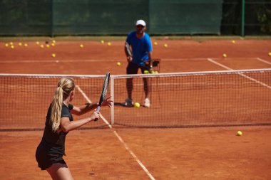 Profesyonel bir tenisçi ve onun koçu tenis kortunda güneşli bir günde antrenman yapıyorlar. Profesyonel bir tenisçinin antrenmanı ve hazırlığı.