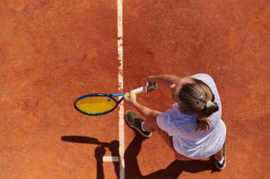 Profesyonel bir bayan tenisçinin üst görüntüsü tenis topunu sahada hassas ve güçlü bir şekilde servis eder.. 