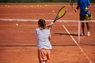 Profesyonel bir tenisçi ve onun koçu tenis kortunda güneşli bir günde antrenman yapıyorlar. Profesyonel bir tenisçinin antrenmanı ve hazırlığı.