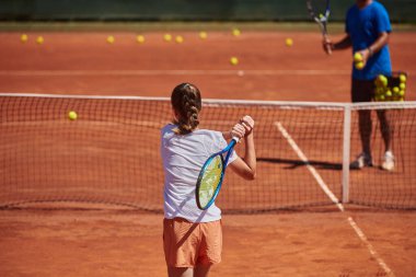 Profesyonel bir tenisçi ve onun koçu tenis kortunda güneşli bir günde antrenman yapıyorlar. Profesyonel bir tenisçinin antrenmanı ve hazırlığı.