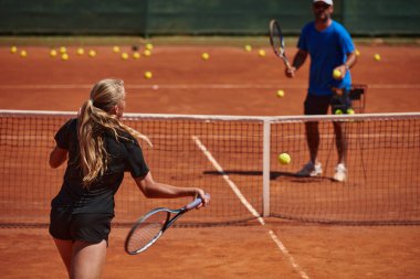 Profesyonel bir tenisçi ve onun koçu tenis kortunda güneşli bir günde antrenman yapıyorlar. Profesyonel bir tenisçinin antrenmanı ve hazırlığı.