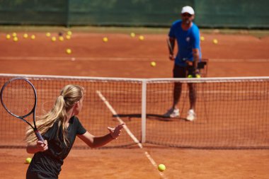 Profesyonel bir tenisçi ve onun koçu tenis kortunda güneşli bir günde antrenman yapıyorlar. Profesyonel bir tenisçinin antrenmanı ve hazırlığı.