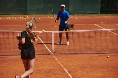 Profesyonel bir tenisçi ve onun koçu tenis kortunda güneşli bir günde antrenman yapıyorlar. Profesyonel bir tenisçinin antrenmanı ve hazırlığı.