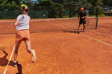Profesyonel bir tenisçi ve onun koçu tenis kortunda güneşli bir günde antrenman yapıyorlar. Profesyonel bir tenisçinin antrenmanı ve hazırlığı.