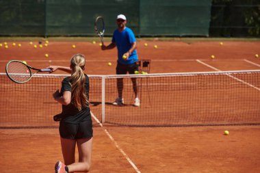 Profesyonel bir tenisçi ve onun koçu tenis kortunda güneşli bir günde antrenman yapıyorlar. Profesyonel bir tenisçinin antrenmanı ve hazırlığı.