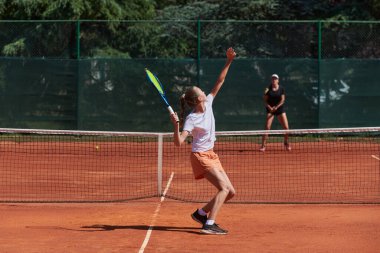 Genç kızlar güneşli bir günde canlı bir tenis maçında modern bir tenis kortunda yeteneklerini ve heveslerini gösteriyorlar.