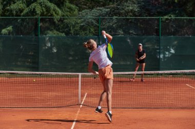 Genç kızlar güneşli bir günde canlı bir tenis maçında modern bir tenis kortunda yeteneklerini ve heveslerini gösteriyorlar.