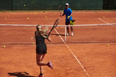 Profesyonel bir tenisçi ve onun koçu tenis kortunda güneşli bir günde antrenman yapıyorlar. Profesyonel bir tenisçinin antrenmanı ve hazırlığı.
