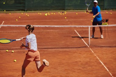 Profesyonel bir tenisçi ve onun koçu tenis kortunda güneşli bir günde antrenman yapıyorlar. Profesyonel bir tenisçinin antrenmanı ve hazırlığı.