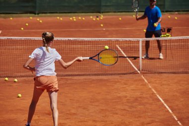 Profesyonel bir tenisçi ve onun koçu tenis kortunda güneşli bir günde antrenman yapıyorlar. Profesyonel bir tenisçinin antrenmanı ve hazırlığı.