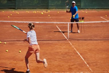 Profesyonel bir tenisçi ve onun koçu tenis kortunda güneşli bir günde antrenman yapıyorlar. Profesyonel bir tenisçinin antrenmanı ve hazırlığı.