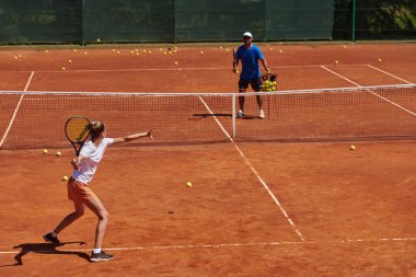 Profesyonel bir tenisçi ve onun koçu tenis kortunda güneşli bir günde antrenman yapıyorlar. Profesyonel bir tenisçinin antrenmanı ve hazırlığı.