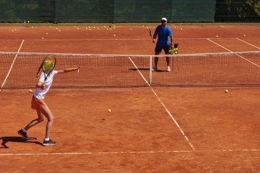 Profesyonel bir tenisçi ve onun koçu tenis kortunda güneşli bir günde antrenman yapıyorlar. Profesyonel bir tenisçinin antrenmanı ve hazırlığı.