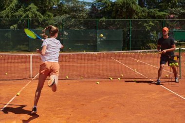 Profesyonel bir tenisçi ve onun koçu tenis kortunda güneşli bir günde antrenman yapıyorlar. Profesyonel bir tenisçinin antrenmanı ve hazırlığı.