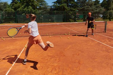 Profesyonel bir tenisçi ve onun koçu tenis kortunda güneşli bir günde antrenman yapıyorlar. Profesyonel bir tenisçinin antrenmanı ve hazırlığı.