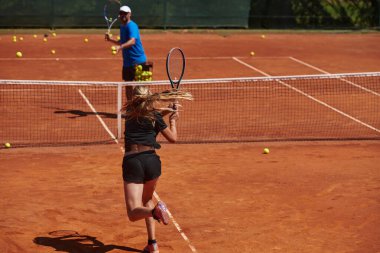 Profesyonel bir tenisçi ve onun koçu tenis kortunda güneşli bir günde antrenman yapıyorlar. Profesyonel bir tenisçinin antrenmanı ve hazırlığı.