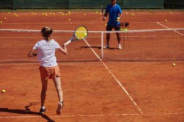 Profesyonel bir tenisçi ve onun koçu tenis kortunda güneşli bir günde antrenman yapıyorlar. Profesyonel bir tenisçinin antrenmanı ve hazırlığı.