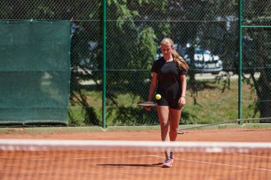 Güneşli bir günde tenis kortunun modern estetiğiyle çevrili profesyonel tenis yetenekleri sergileyen genç bir kız.