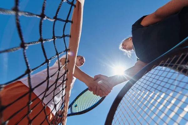 在一个阳光灿烂的日子里 两名女网球选手微笑着握手 在一场比赛之后 展现了运动员的风范和友谊 — 图库照片