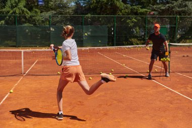 Profesyonel bir tenisçi ve onun koçu tenis kortunda güneşli bir günde antrenman yapıyorlar. Profesyonel bir tenisçinin antrenmanı ve hazırlığı.