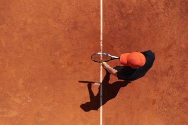 Profesyonel bir tenisçinin üst görüntüsü, tenis topunu hassas ve güçlü bir şekilde sahada servis eder.. 