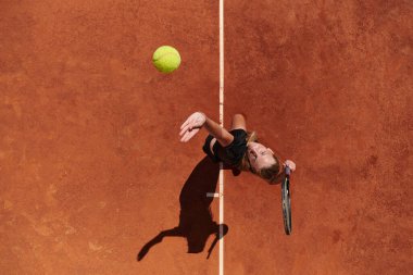 Profesyonel bir bayan tenisçinin üst görüntüsü tenis topunu sahada hassas ve güçlü bir şekilde servis eder.. 