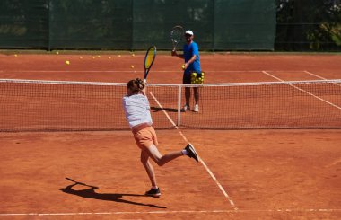 Profesyonel bir tenisçi ve onun koçu tenis kortunda güneşli bir günde antrenman yapıyorlar. Profesyonel bir tenisçinin antrenmanı ve hazırlığı.