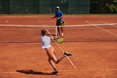 Profesyonel bir tenisçi ve onun koçu tenis kortunda güneşli bir günde antrenman yapıyorlar. Profesyonel bir tenisçinin antrenmanı ve hazırlığı.