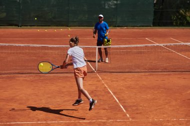 Profesyonel bir tenisçi ve onun koçu tenis kortunda güneşli bir günde antrenman yapıyorlar. Profesyonel bir tenisçinin antrenmanı ve hazırlığı.