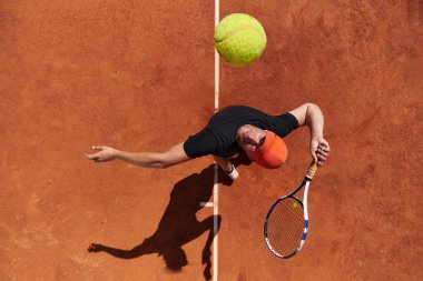 Profesyonel bir tenisçinin üst görüntüsü, tenis topunu hassas ve güçlü bir şekilde sahada servis eder.. 