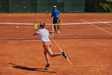 Profesyonel bir tenisçi ve onun koçu tenis kortunda güneşli bir günde antrenman yapıyorlar. Profesyonel bir tenisçinin antrenmanı ve hazırlığı.