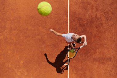 Profesyonel bir bayan tenisçinin üst görüntüsü tenis topunu sahada hassas ve güçlü bir şekilde servis eder.. 